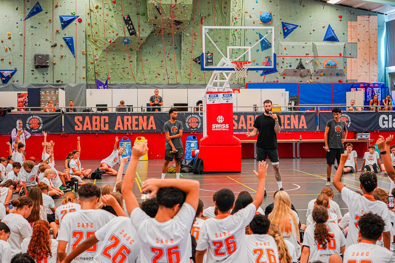 Teilnehmerinnen und Teilnehmer des Swiss Allstar Basketball Camps in der Mehrzweckhalle Zofingen, mit erhobenen Händen während einer Ansprache